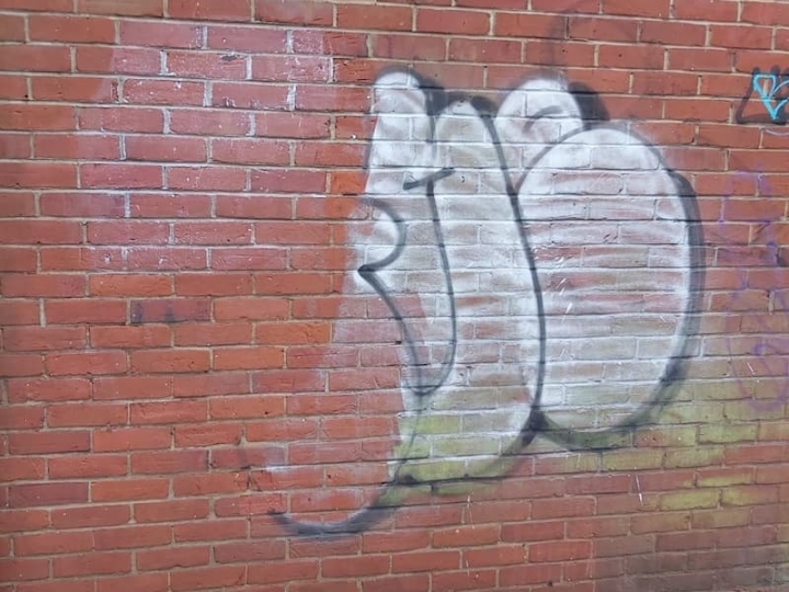 A red brick wall in Great Yarmouth, after attack by graffiti vandalism, requiring thorough cleaning and professional graffiti removal services to restore the integrity and appearance of the structure.