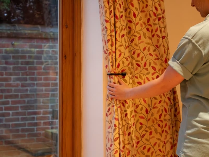 A woman offers a tailored solution by tidying up the curtains, showcasing her attention to detail and commitment to personalised service.
